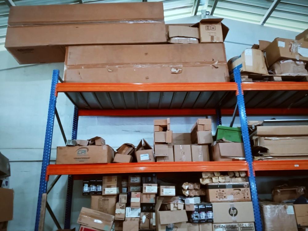Cajas de repuestos alineadas en estantes de rack bajo el techo de lámina del almacén